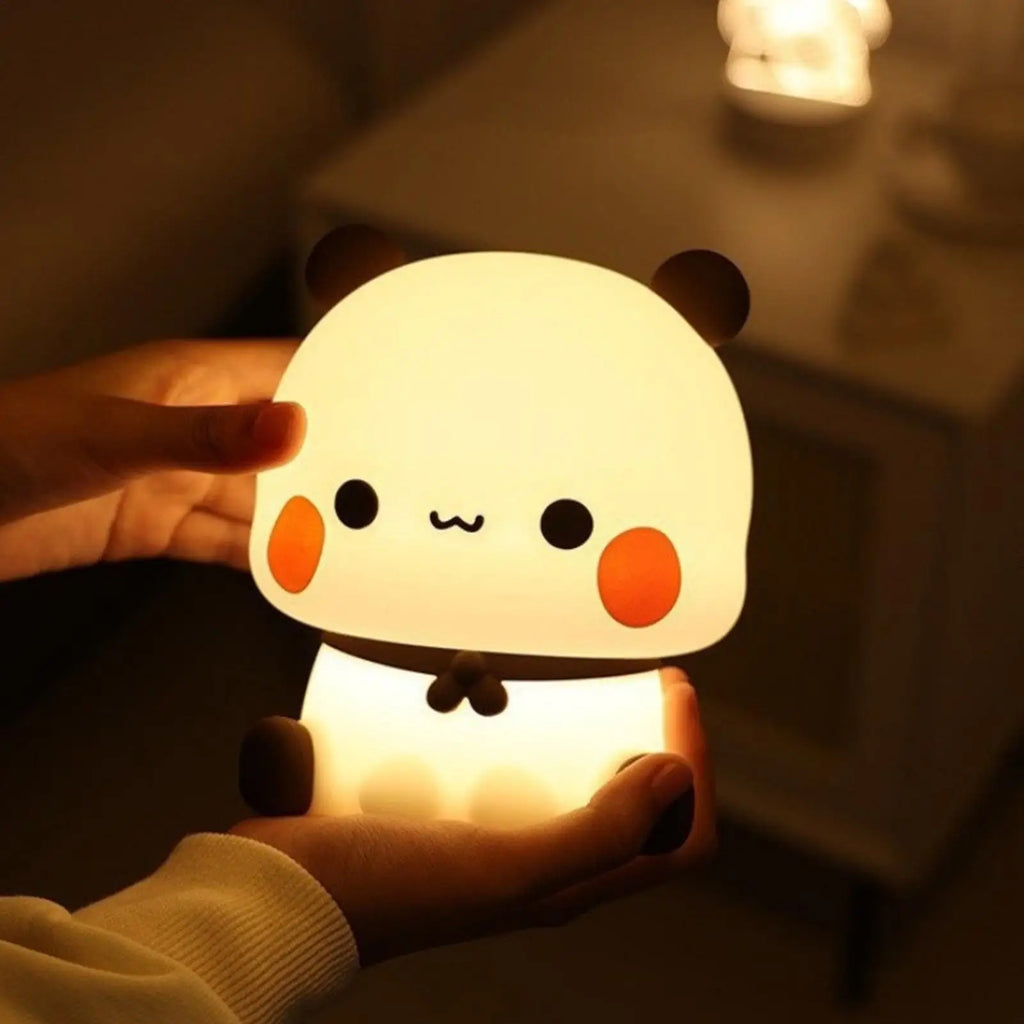 Bear silicone LED lamp being gently held in both hands, showing compact size