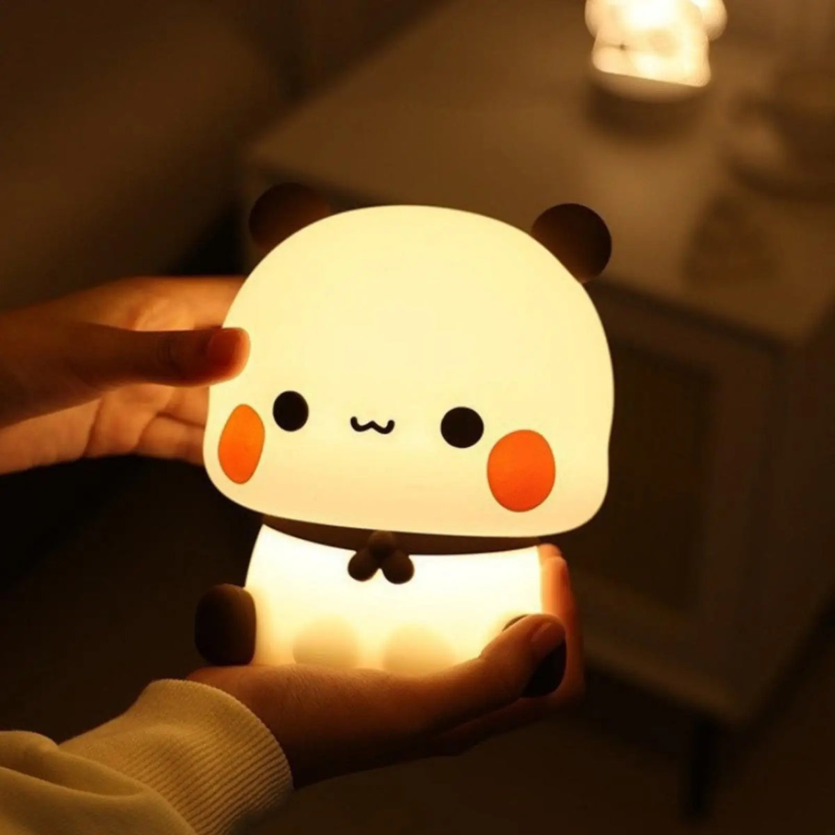 Bear silicone LED lamp being gently held in both hands, showing compact size
