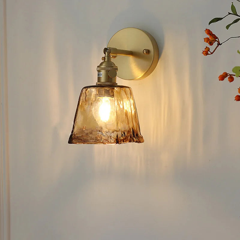 Amber stained glass wall lamp on white wall with brass fixture, warm light on
