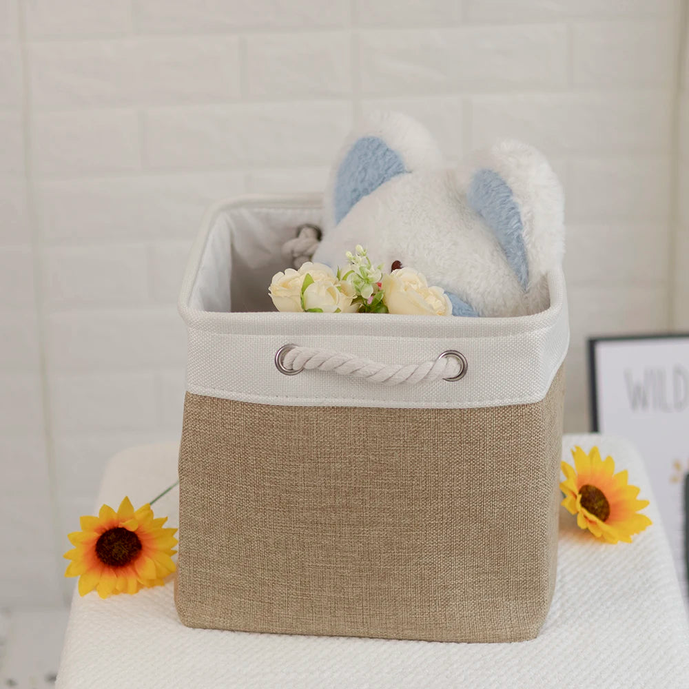 Square fabric storage cube in khaki color holding stuffed animal and flowers, placed on a surface with sunflower decoration