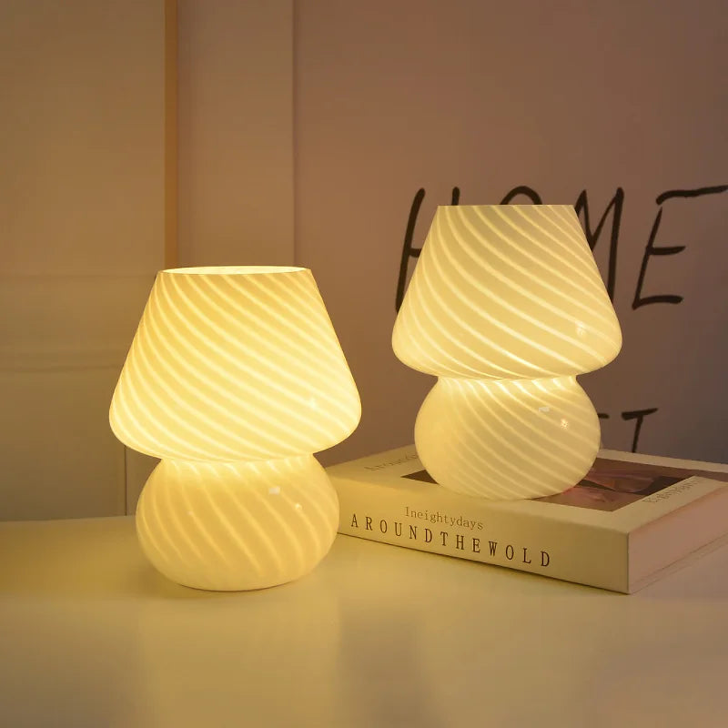 two white glass mushroom lamps emitting a warm glow on a book in a cozy room setting
