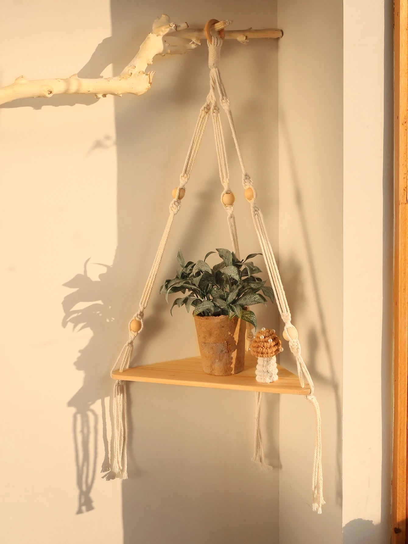 Single wooden corner shelf with cream macrame cords and beads, holding a plant
