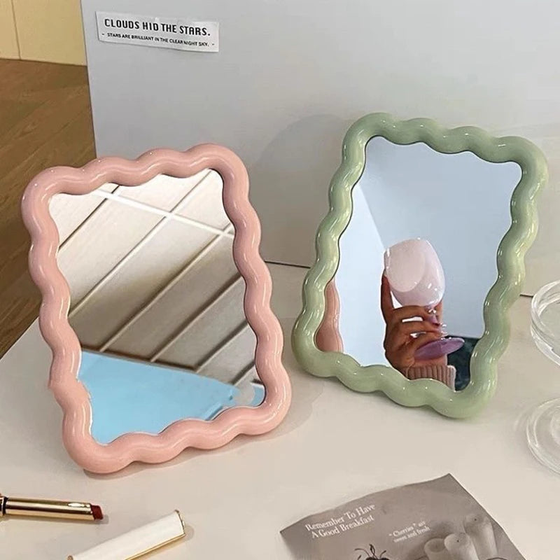 Pink and green scalloped edge mirrors on a desk, reflecting a cozy interior.