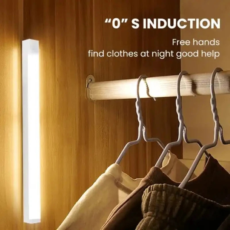 LED night light mounted vertically inside a wooden closet next to hanging clothes