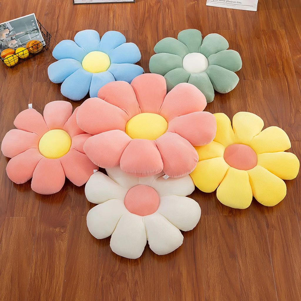 Grouping of bright daisy pillows in multiple colors arranged on wood floor