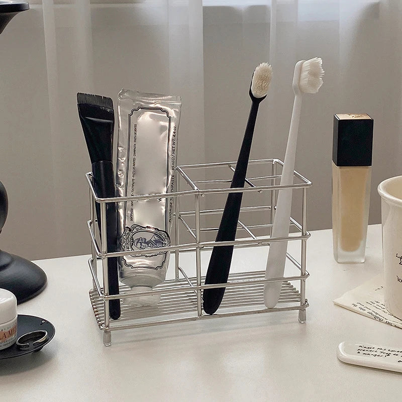 Smaller stainless steel holder with two toothbrushes and toothpaste on a vanity surface
