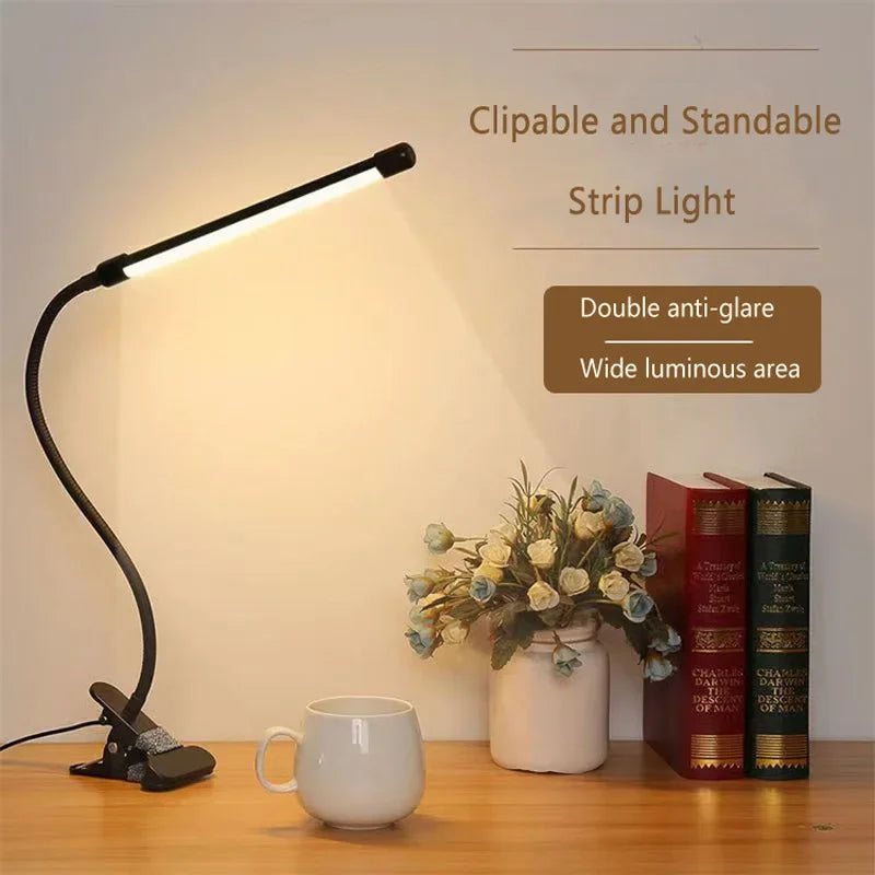 Warm light from clip-on LED lamp on a desk with books, cup, and flowers