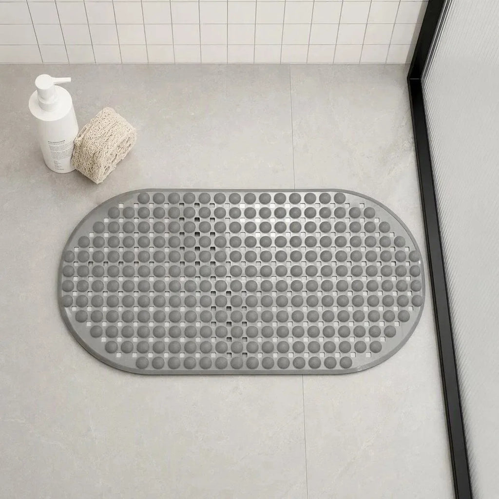 Oval gray non-slip bath mat with textured surface placed on a bathroom floor