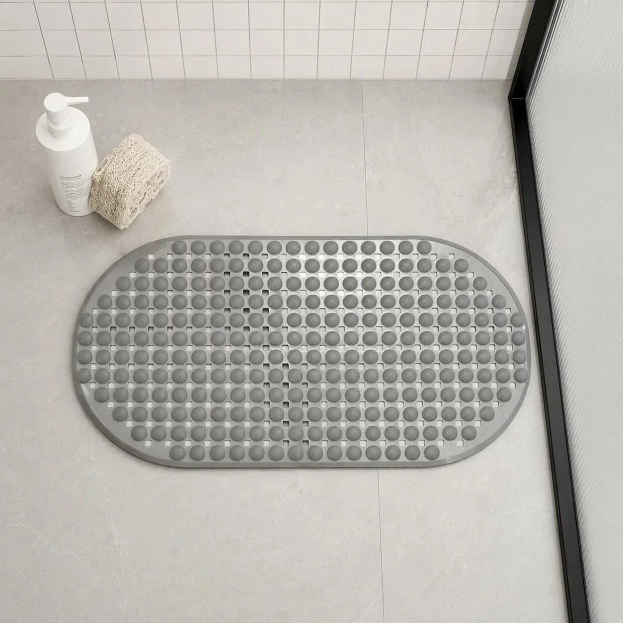 Oval gray non-slip bath mat with textured surface placed on a bathroom floor