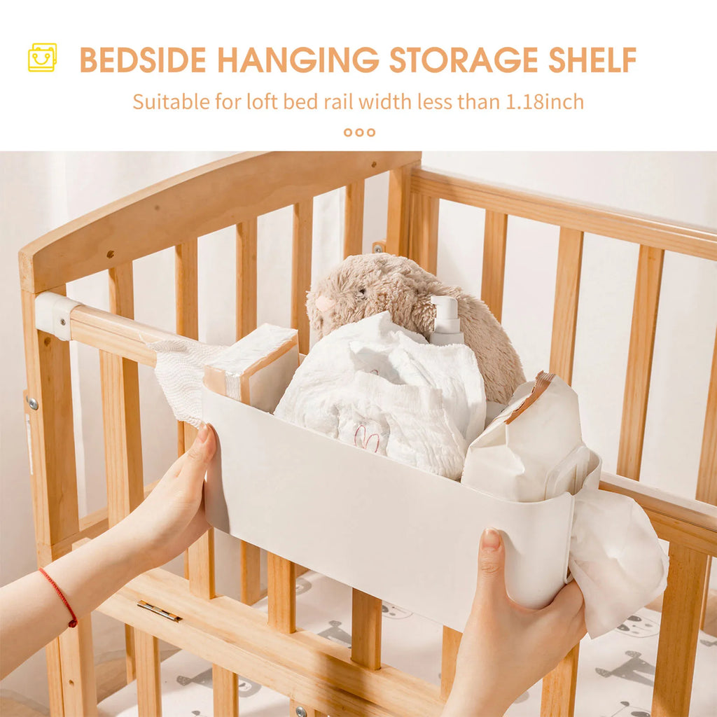 Bedside hanging storage shelf hooked over a wooden crib rail, holding toys and nursery items