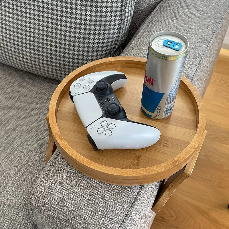 Bamboo sofa armrest tray with a game controller and drink can on a grey sofa