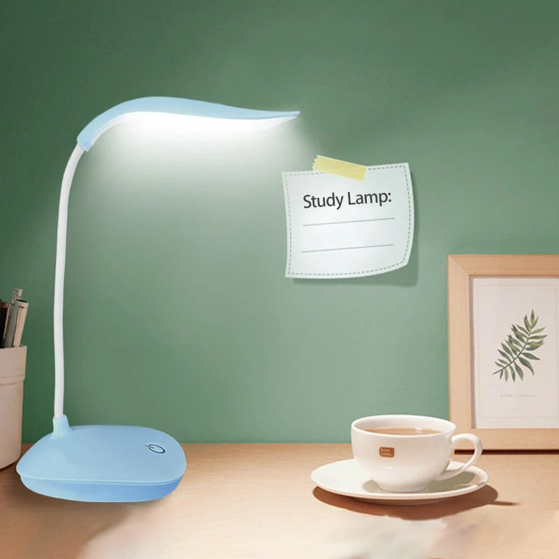 blue LED desk lamp on study desk with cup and framed print