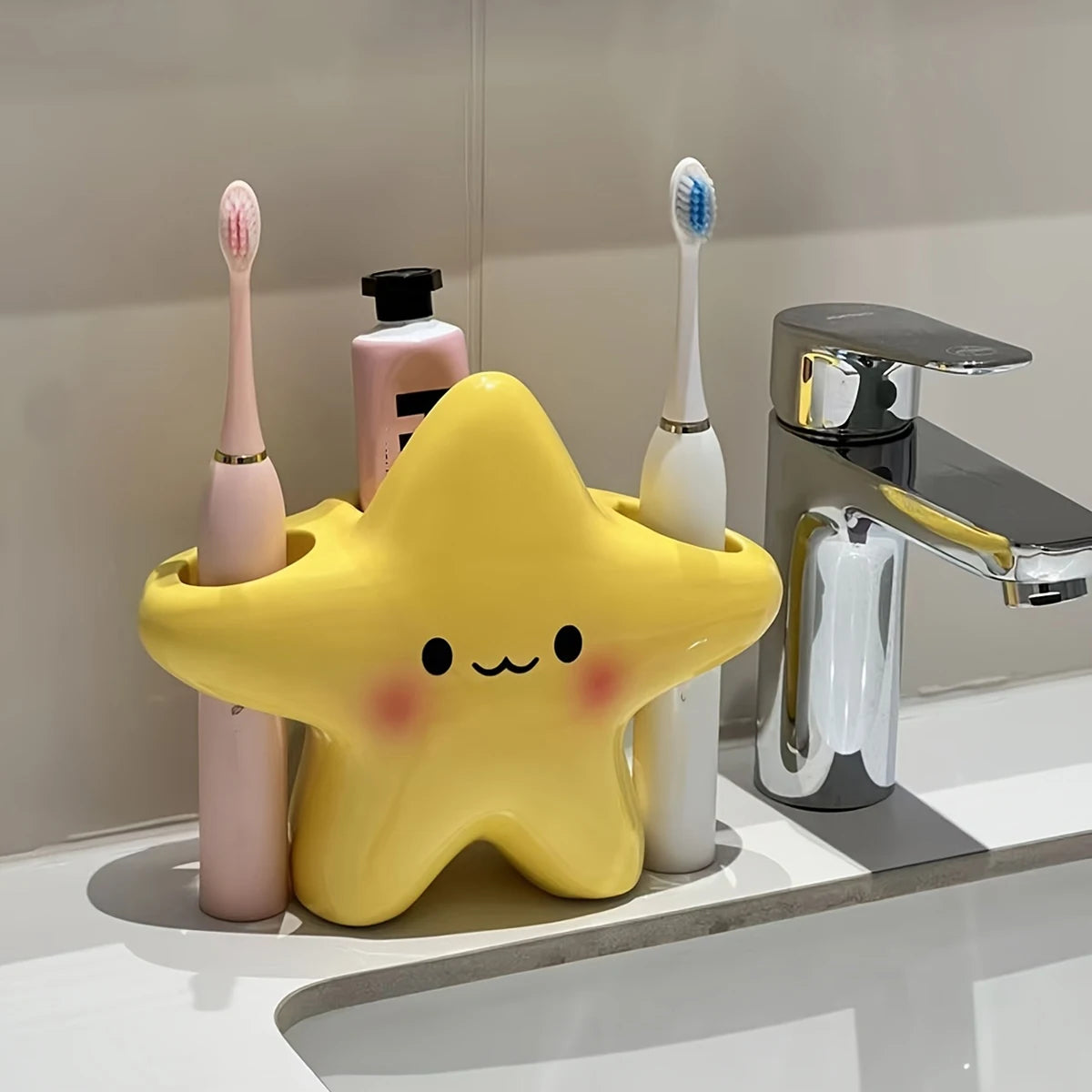 Yellow star-shaped toothbrush holder with smiling face, holding electric toothbrushes and toothpaste on a bathroom counter