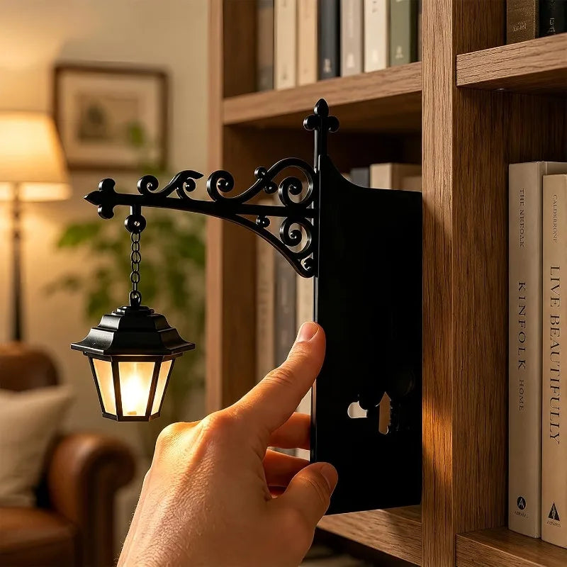 Hand placing a vintage black iron lantern book nook lamp beside books on a shelf