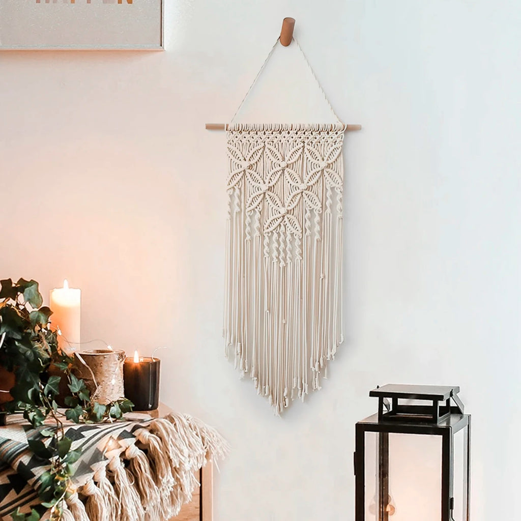 Beige handwoven macrame wall hanging displayed above a cozy console with candles
