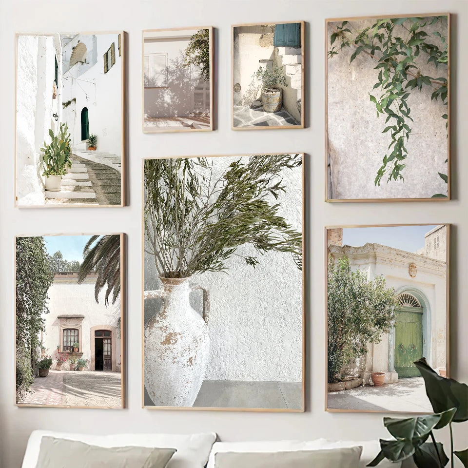 Gallery wall arrangement of unframed canvas prints featuring Spanish architecture and green plants