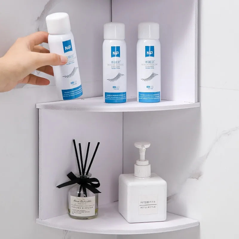 hand placing bottles on a white plastic corner wall shelf holding bathroom items