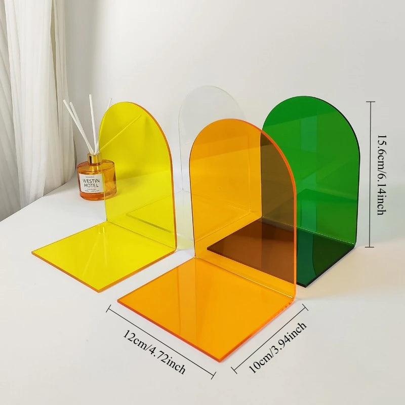 Yellow, clear, and green acrylic bookends on a desk with measurements displayed for height, depth, and width