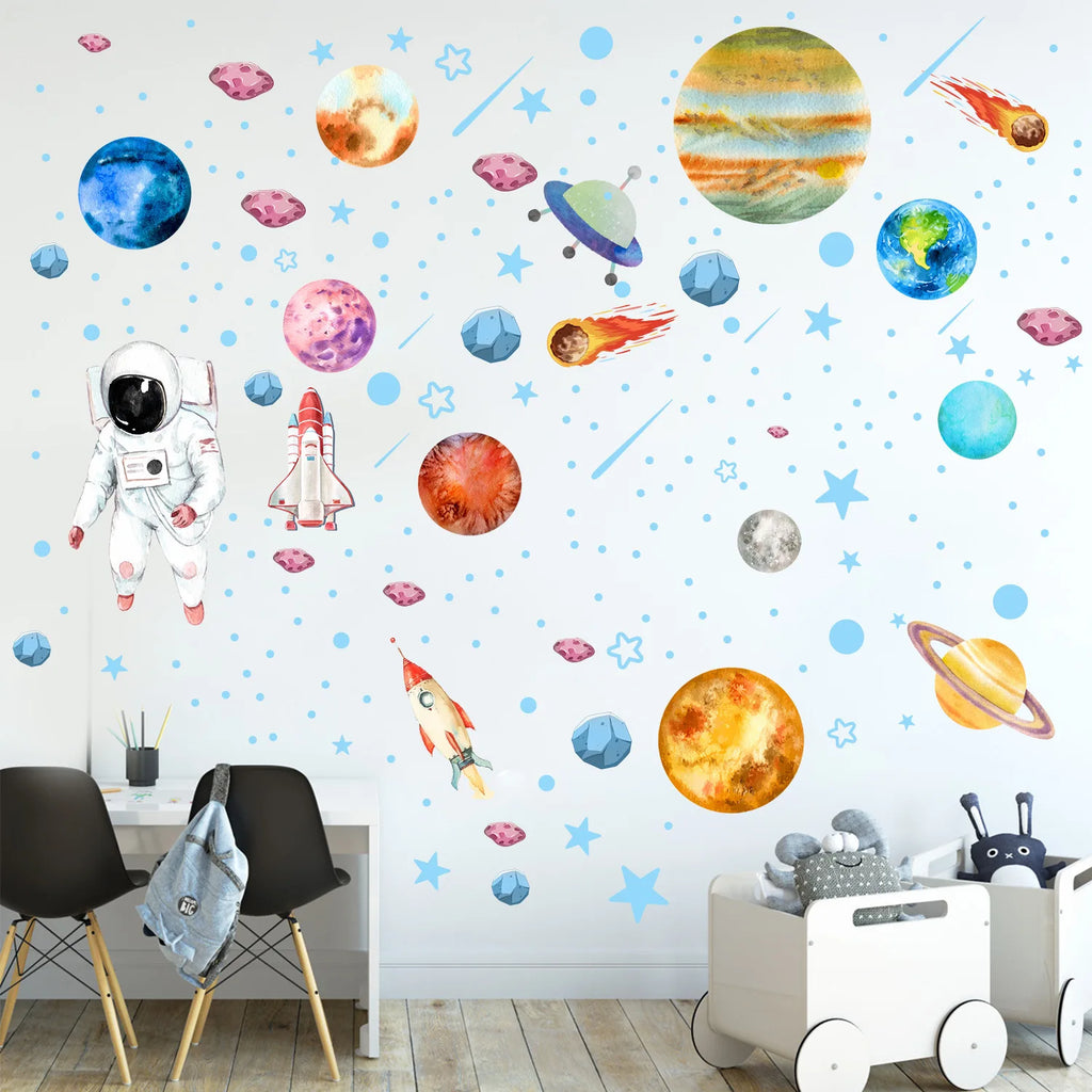 space theme planet and astronaut wall decals above small workspace and toy cart in kids bedroom