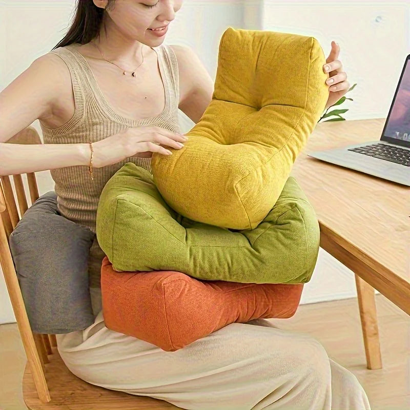 Person holding and stacking three u-shape lumbar support cushions in yellow, green, and orange