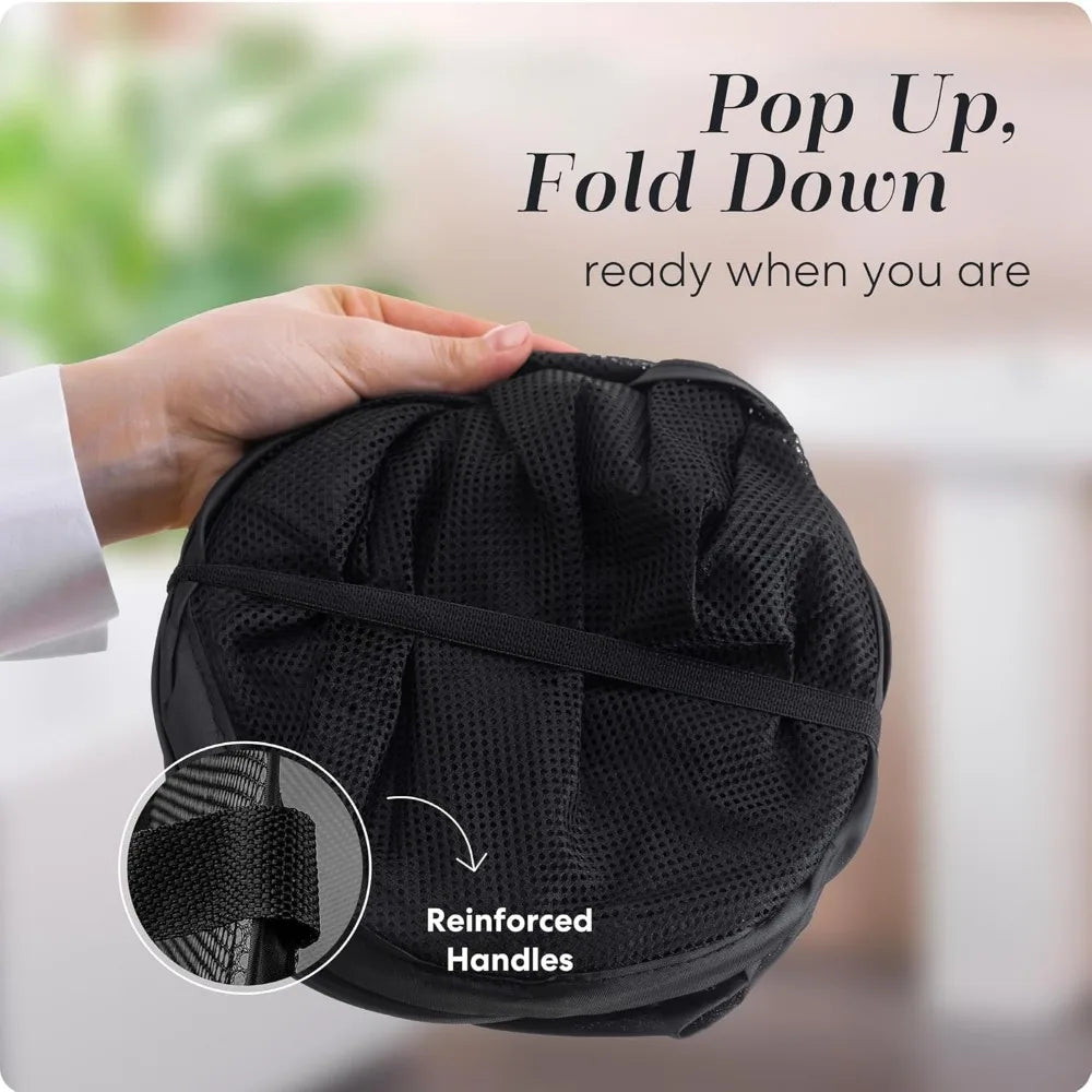 Hand holding folded collapsible black mesh laundry hamper showing reinforced handles