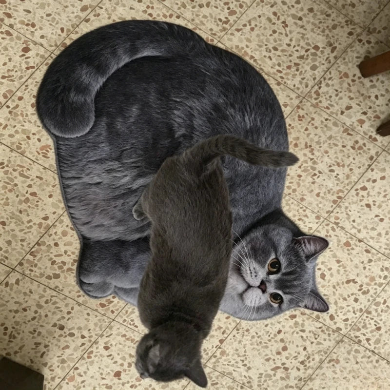 Gray cat-shaped bath rug on tile floor with a real cat beside it