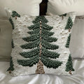 Decorative pillow cover with green evergreen tree print on white fabric, styled on a bed