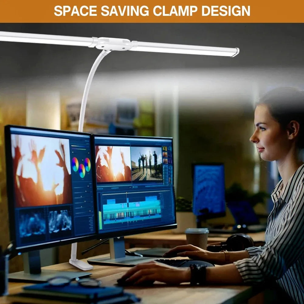 Woman using a space-saving clamp LED desk lamp at a workstation with dual monitors