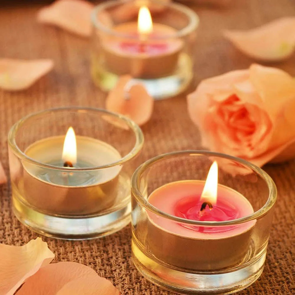 Tealight candle holders with lit tealights on a woven surface among peach rose petals