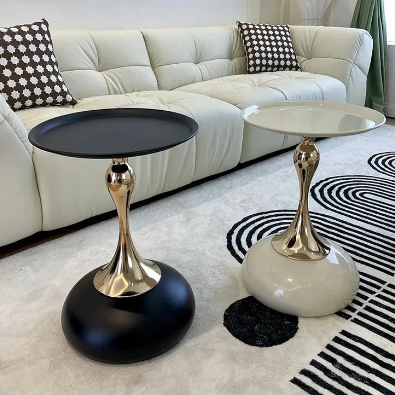 Two modern metal round side tables, one black and one white, beside a cream couch in a living room