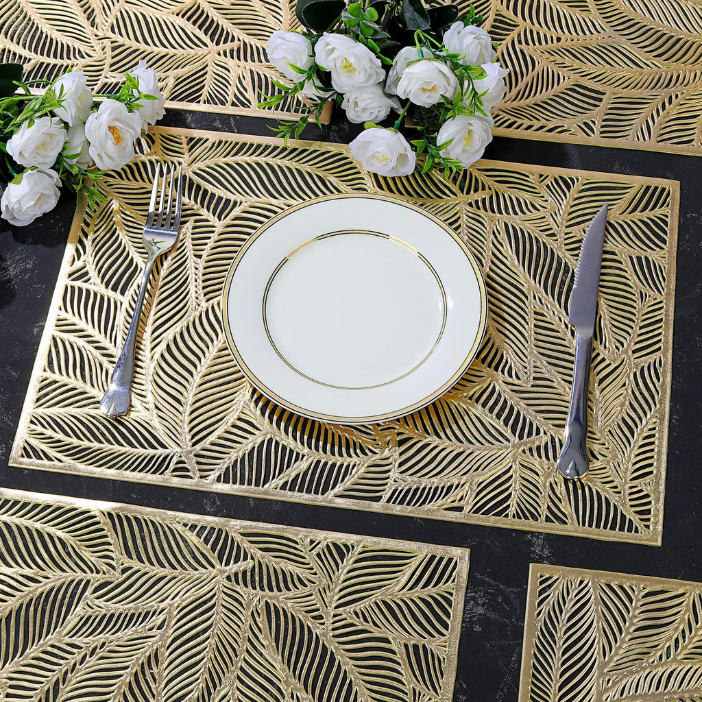 Gold leaf cutout PVC placemats on a dining table set with white dinnerware and flowers