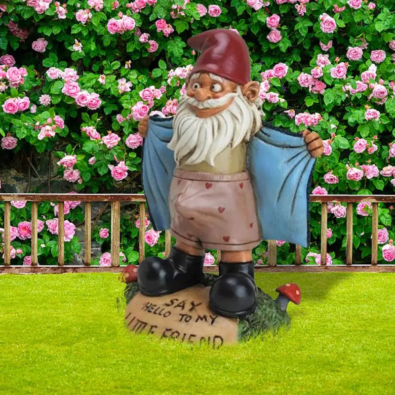 Garden gnome statue in pink shorts displayed outdoors with a rose bush backdrop
