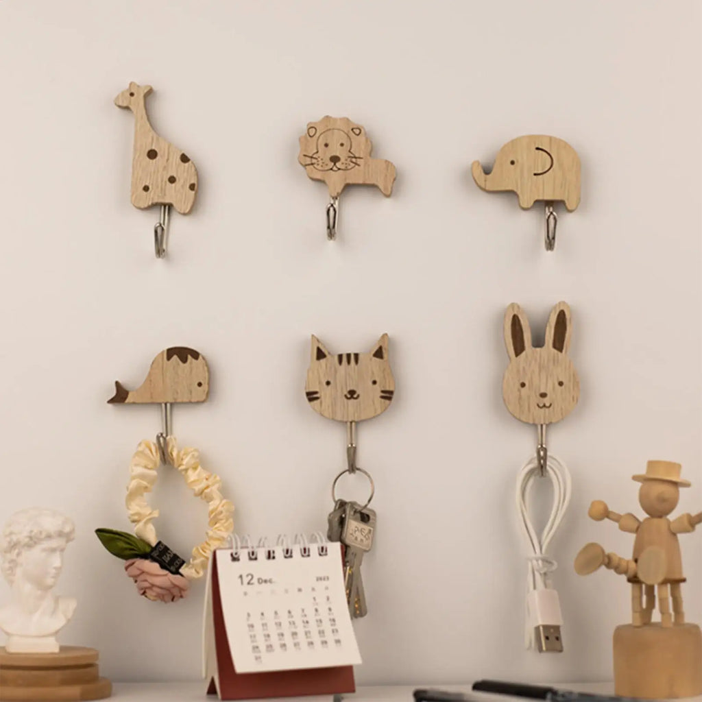 animal wall hooks arranged on a white wall used to hang keys, a hair accessory, cables, and decor in a tidy child’s room