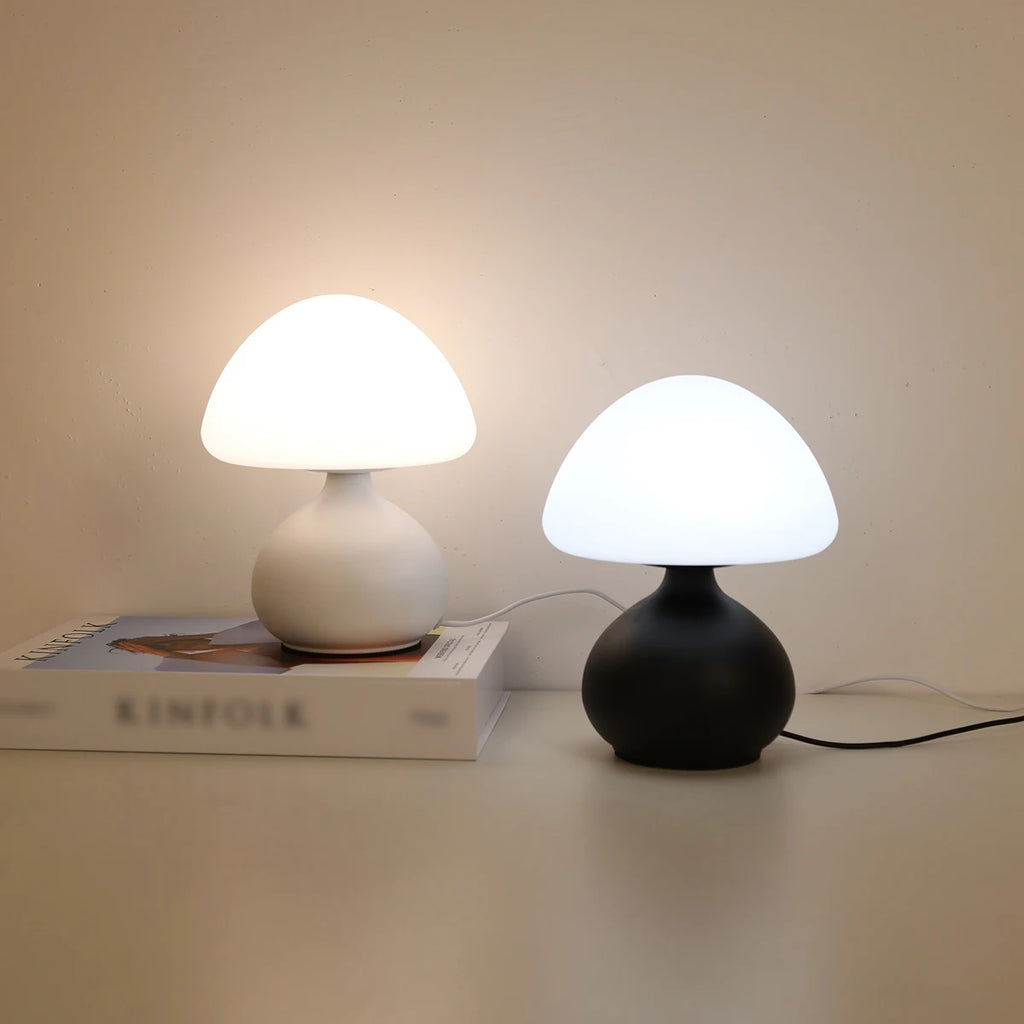 Black and white mushroom table lamps side by side, both lit on a tabletop