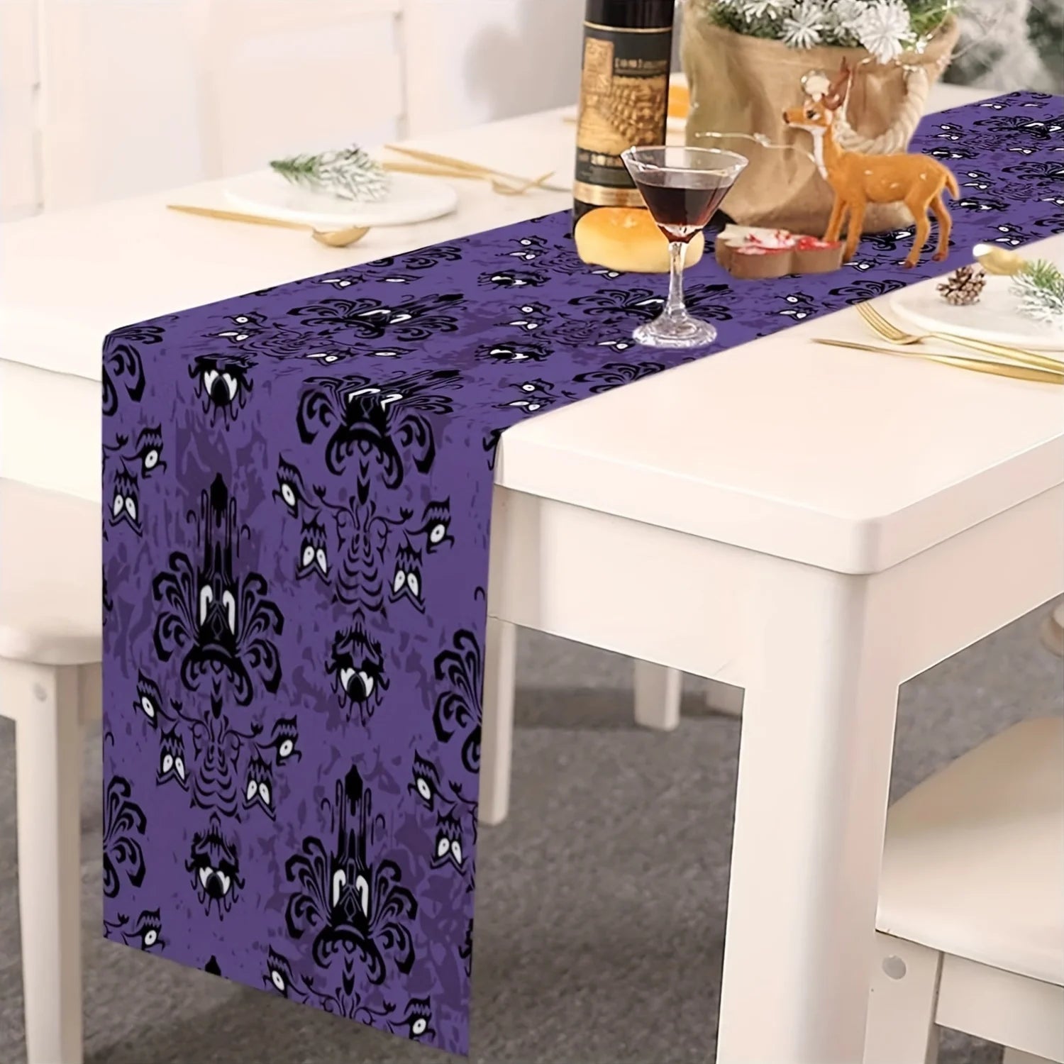 Purple haunted table runner with ghost faces on white dining table, styled with holiday accents