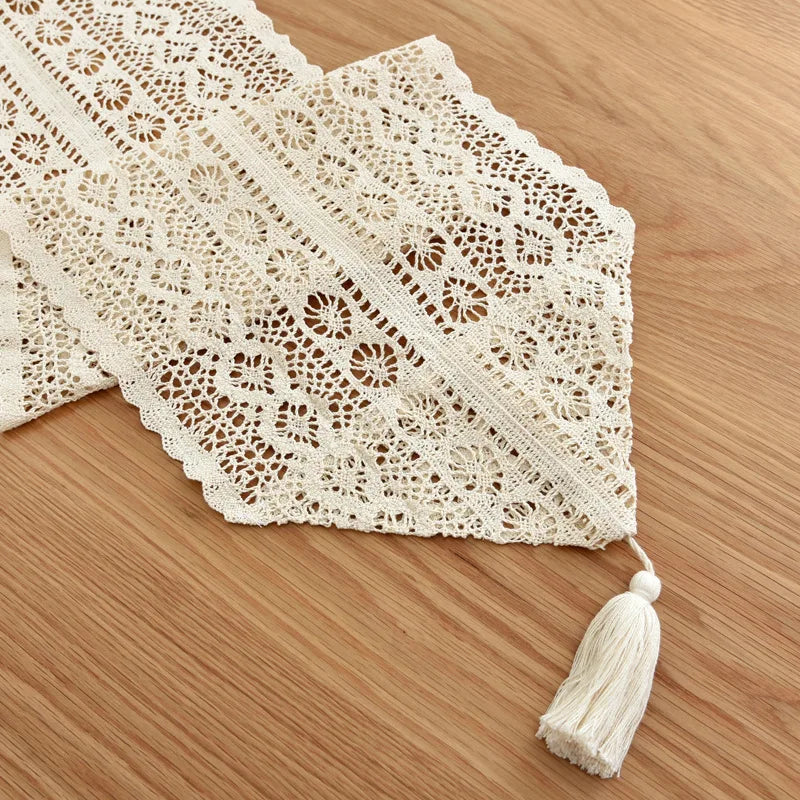 Angle view of crochet lace table runner with tassel detail on wooden surface
