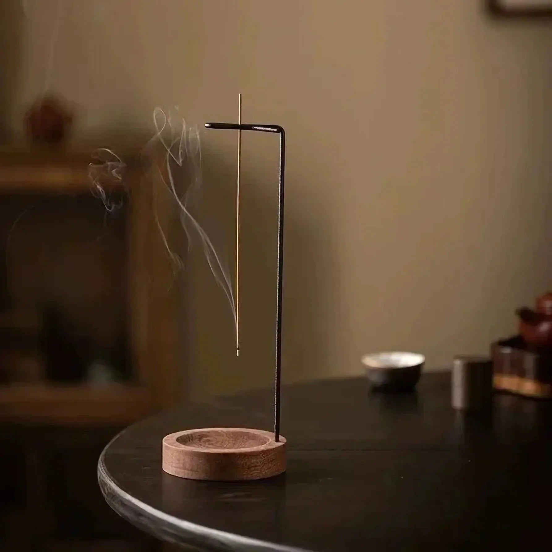 Upright incense holder with round wooden base catching ash, used on a living room side table