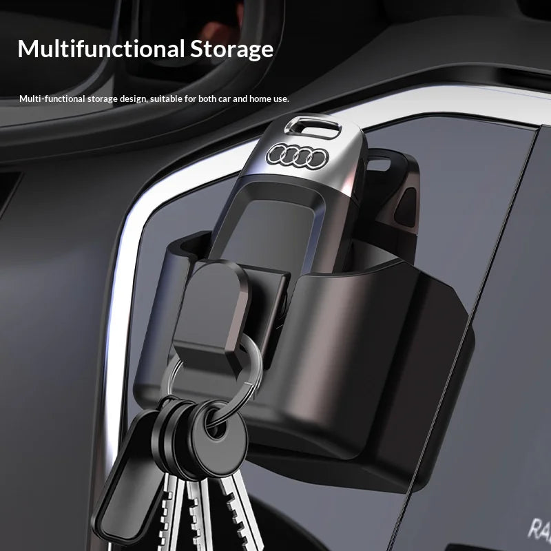 Black rectangular car key storage box attached to a dashboard, holding keys and a car key fob