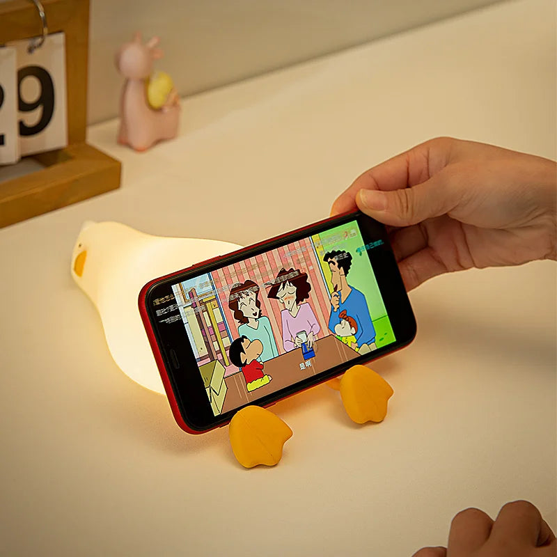 Duck-shaped night light being used as a phone holder on a desk
