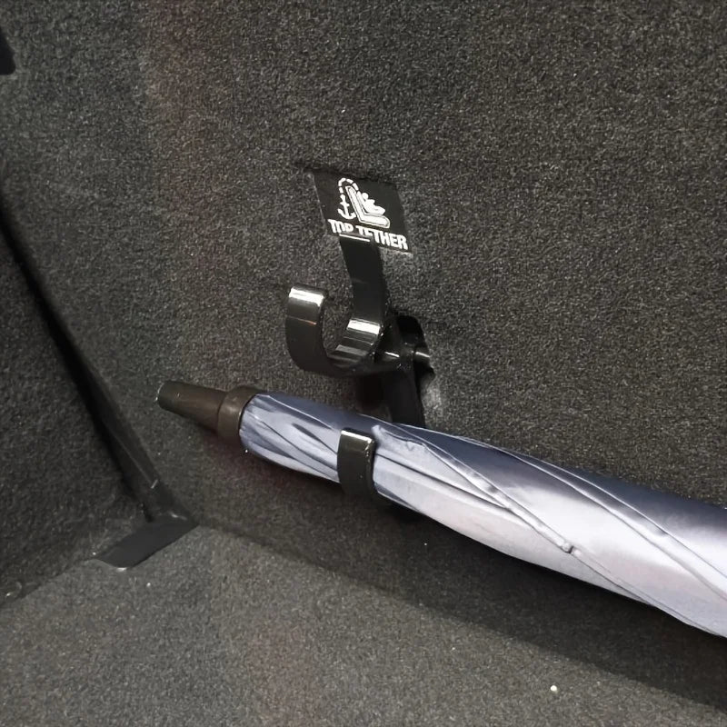Black umbrella secured in sedan trunk using a single storage hook