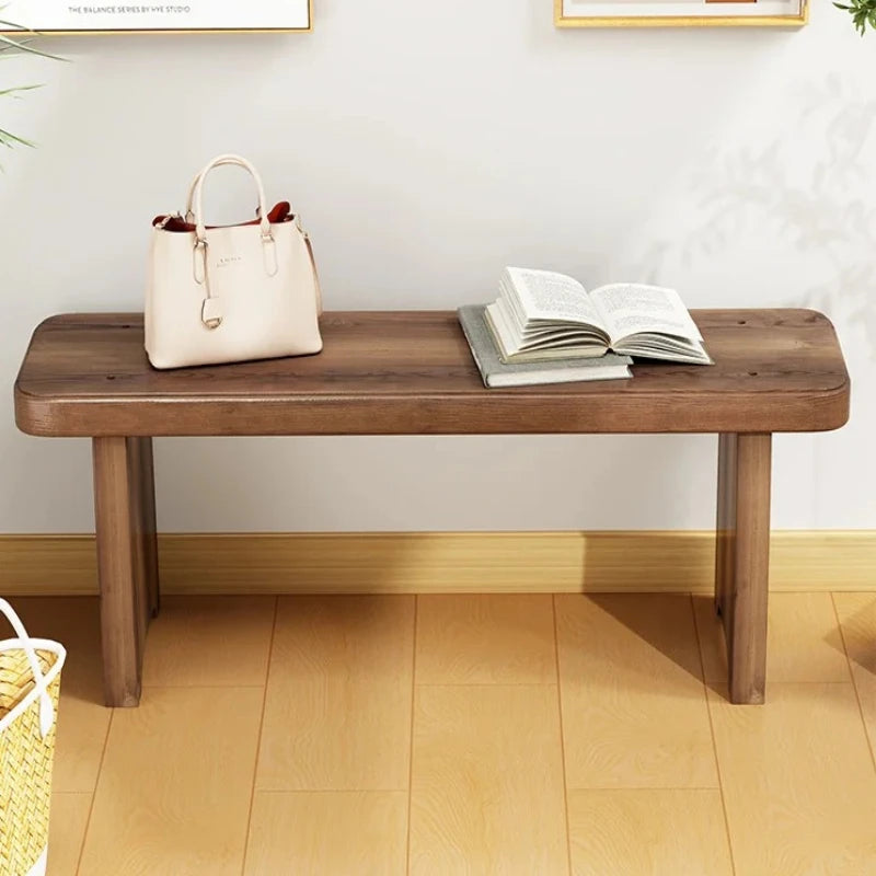 solid wood bench with a pale handbag and an open book resting on top