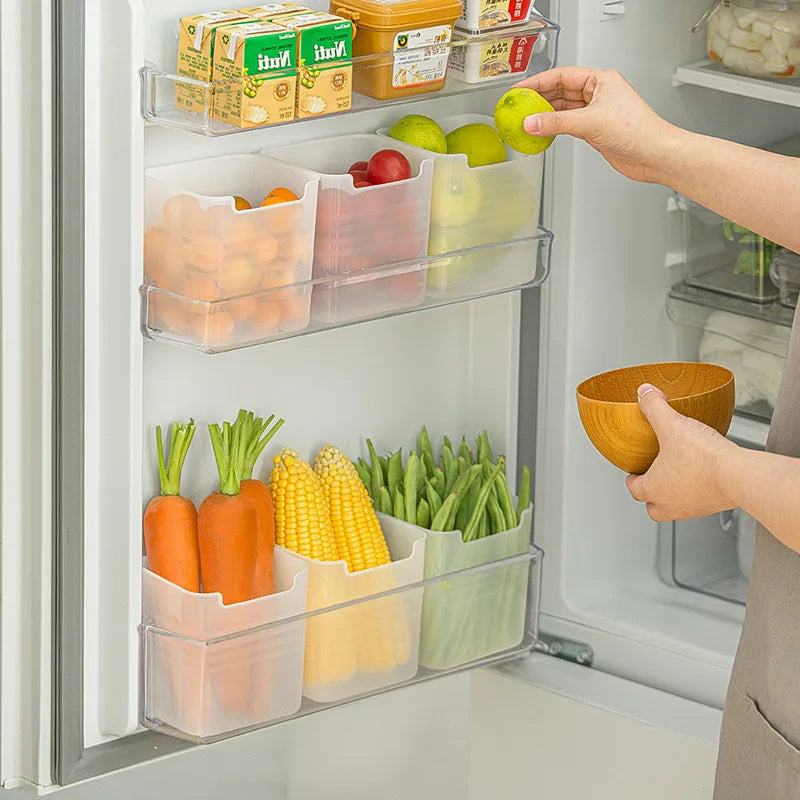 Hand placing limes into a clear plastic fridge door organizer bin with carrots, corn, and green beans stored below