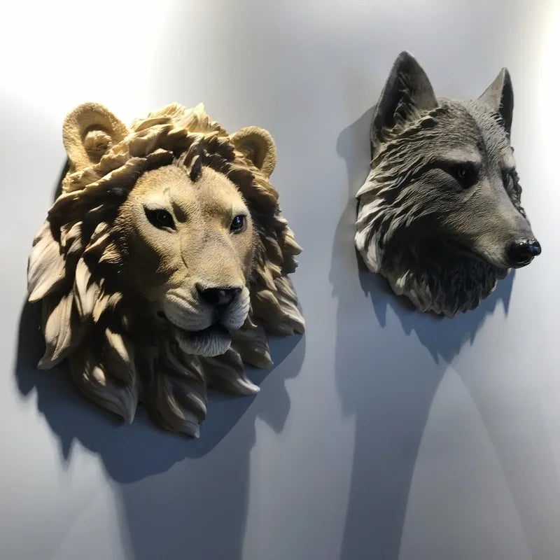 Lifelike resin lion and wolf head wall sculptures mounted side-by-side on a light wall