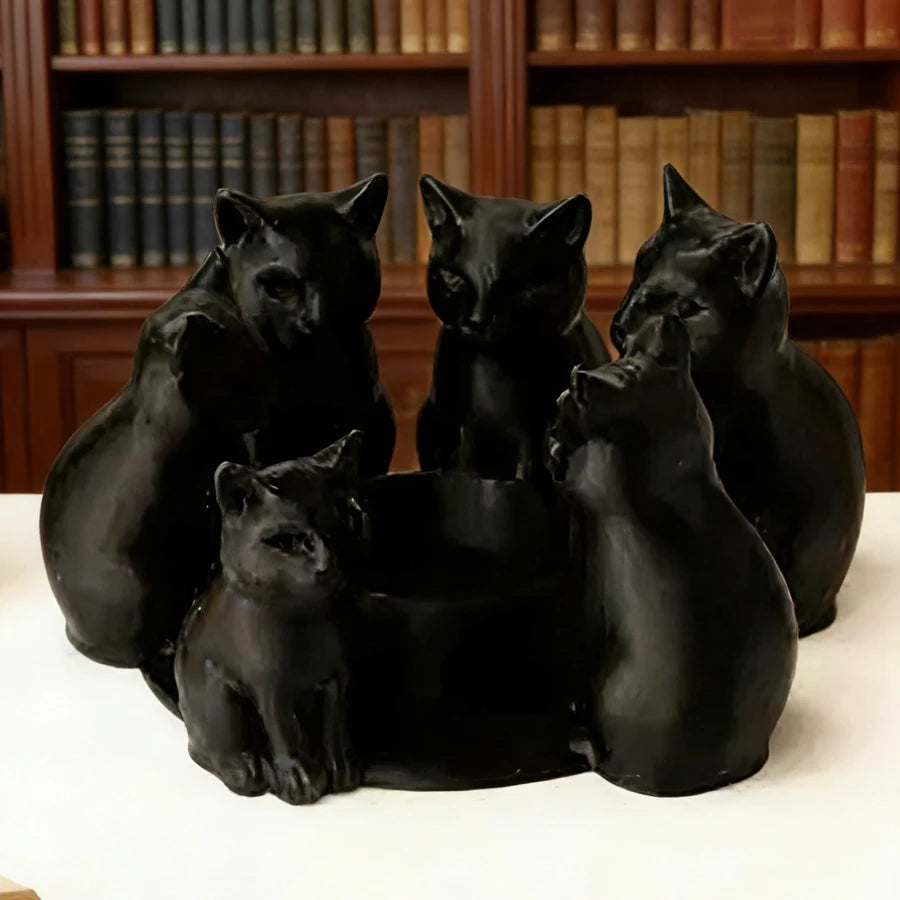 Black cat themed candle holder without candle, shown on a white table with bookshelves behind