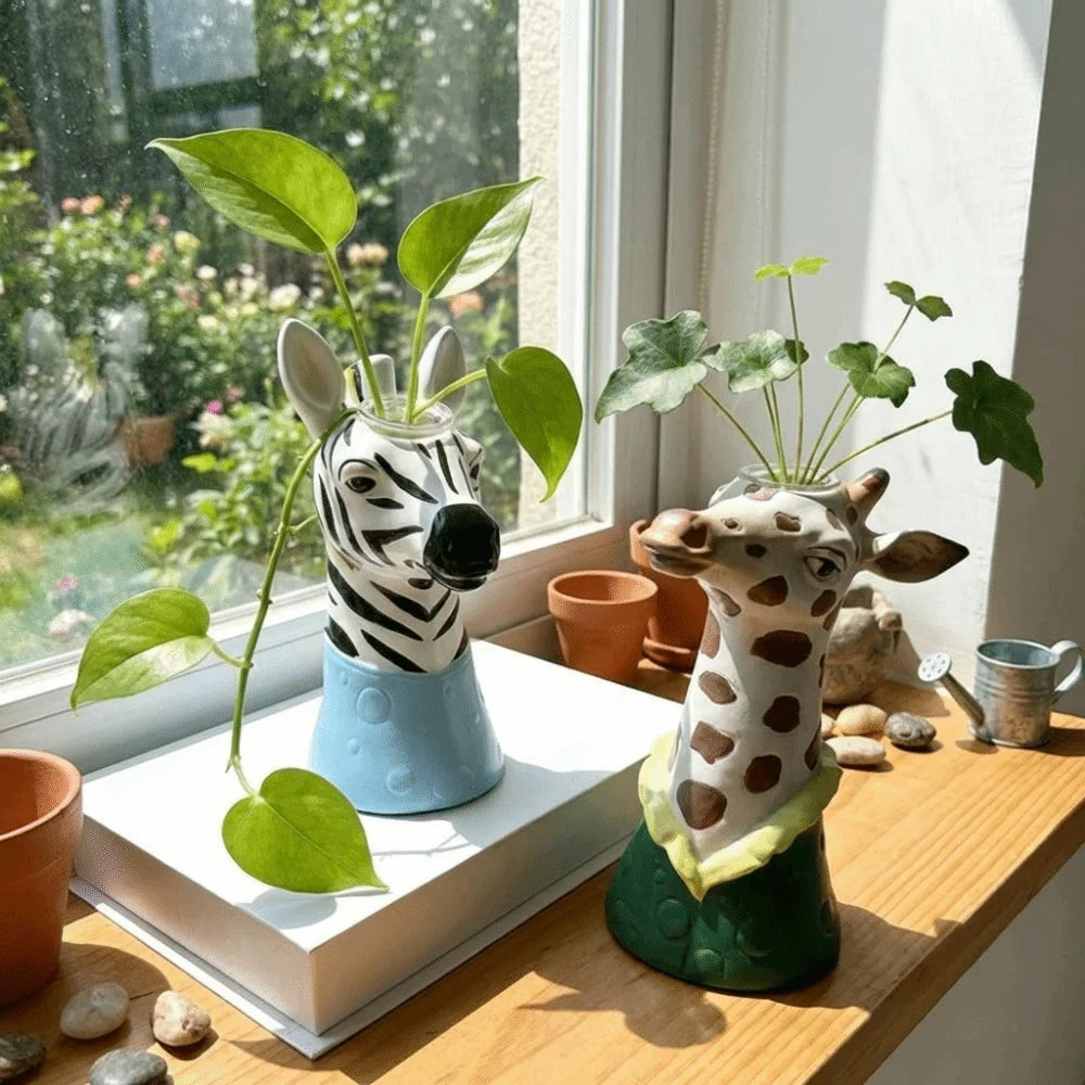 Zebra and giraffe animal head vases displayed on a sunny windowsill
