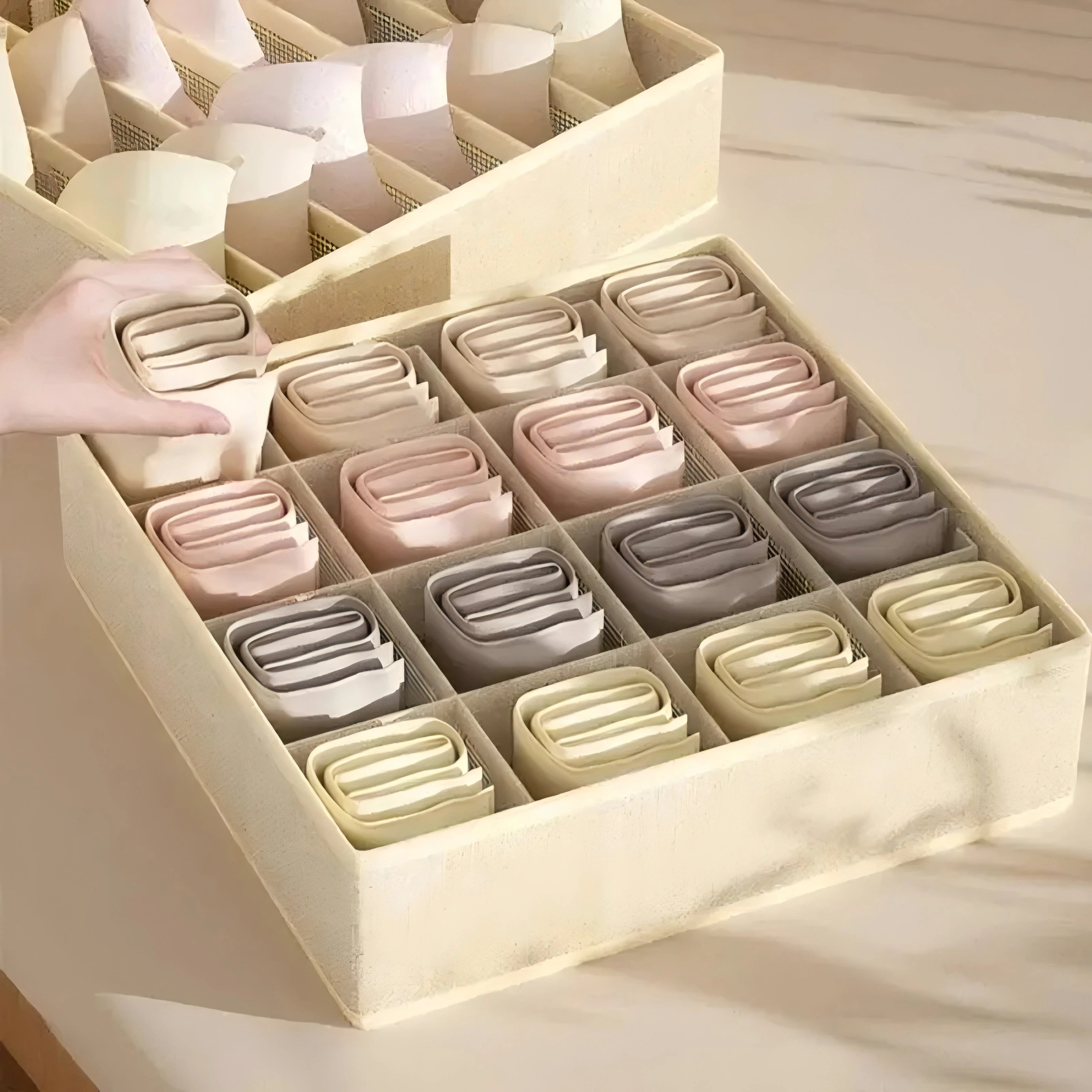 Hand placing a pair of folded socks into a grid compartment of the fabric organizer
