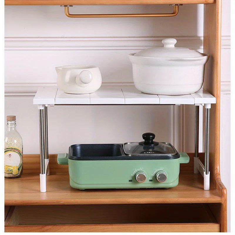 Expandable kitchen counter shelf used for small appliances and serving ware on a wooden shelf