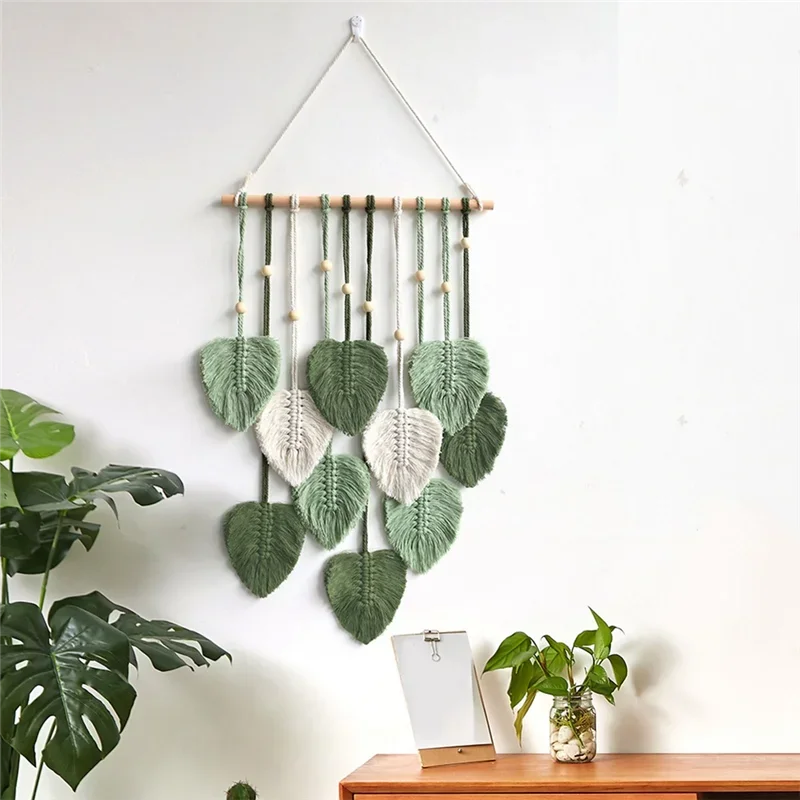 Macrame leaf wall hanging in green tones styled with plants in a living room
