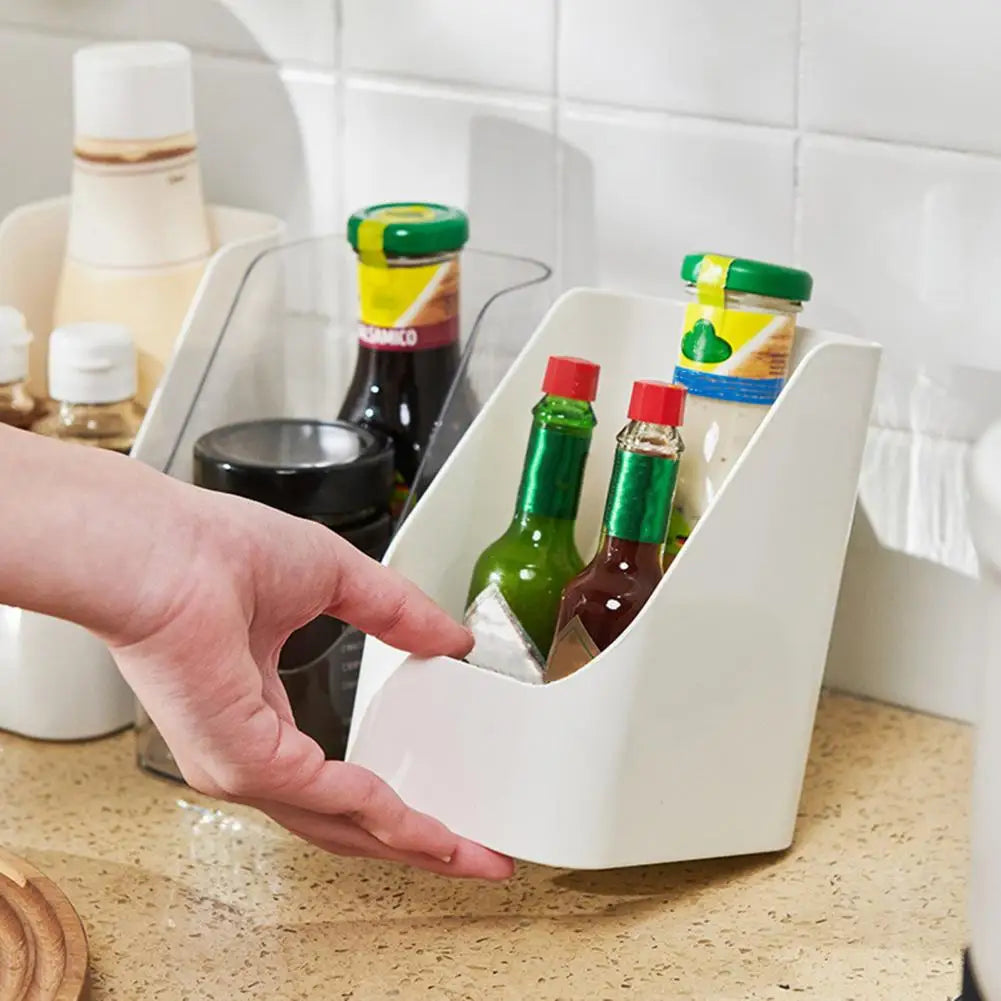 Hand removing a white organizer bin with bottles from a kitchen counter