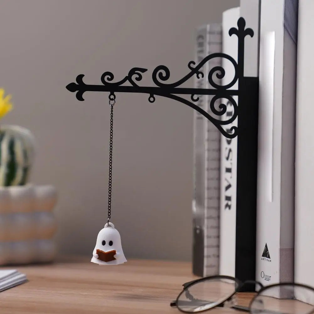 Black iron bookshelf lamp with hanging ghost lantern on a wooden desk between books